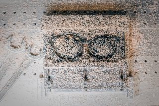 Eine Nahaufnahme von einem Brillengestell, das aus einer Kunststoffplatte gefräst wurde. Die Vertiefung ist mit hellen Spänen und -staub gefüllt.